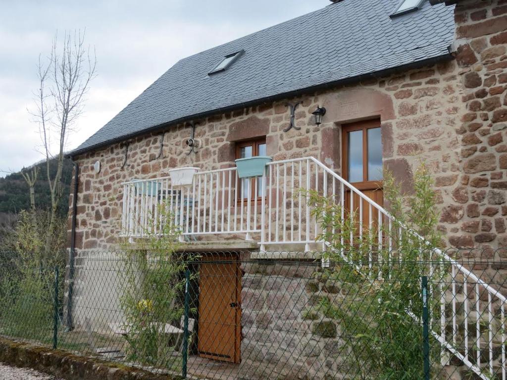 une maison en pierre avec un escalier sur son côté dans l'établissement Gîte dans la Vallée du Lot, à Canilhac
