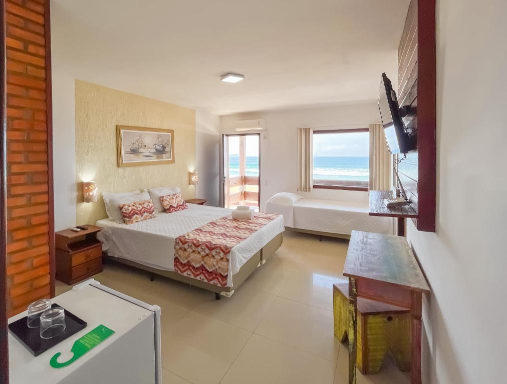 Quarto na Pousada do Albatroz com cama de casal, varanda com vista para o mar, televisão e frigobar