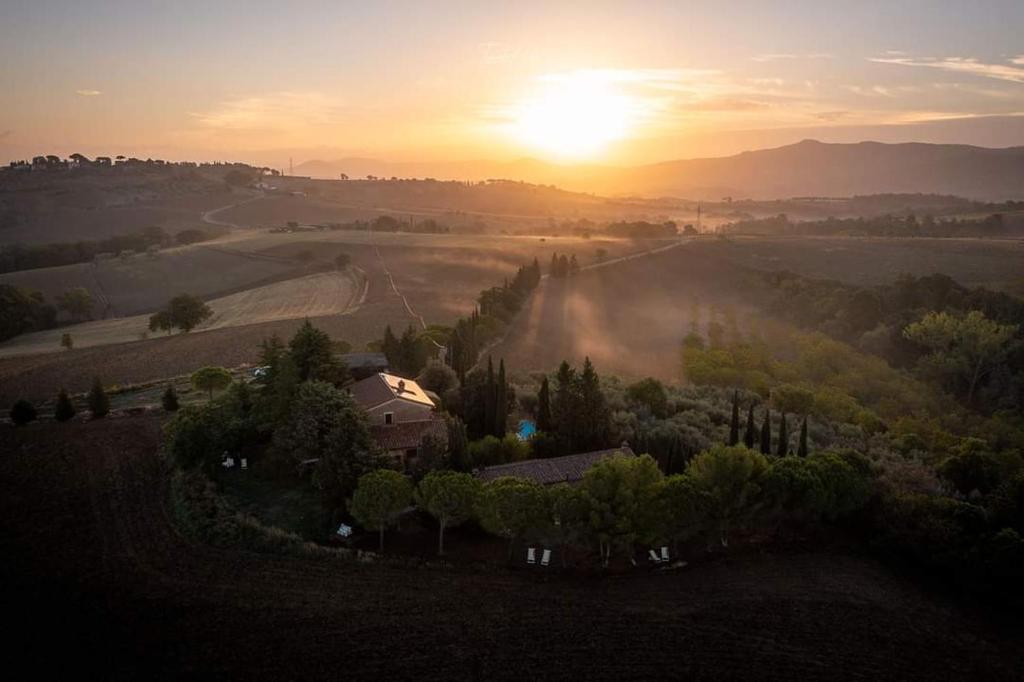 a house in a field with the sunset in the background at Agriturismo La Casetta del Sole in Villastrada