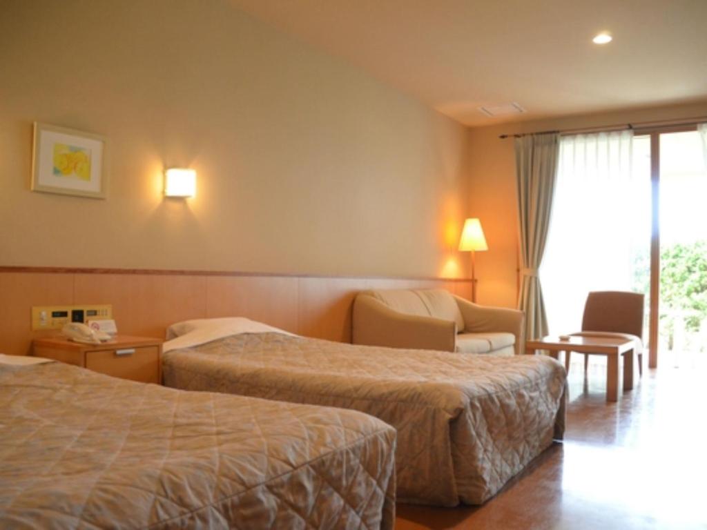 a hotel room with two beds and a chair at Bokkai Onsen Seaside Villa Bokkai - Vacation STAY 69007v in Shika