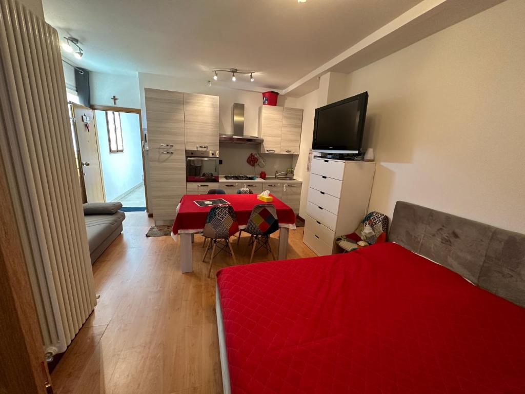 uma sala de estar com uma cama vermelha e uma cozinha em monolocale in centro em Asiago