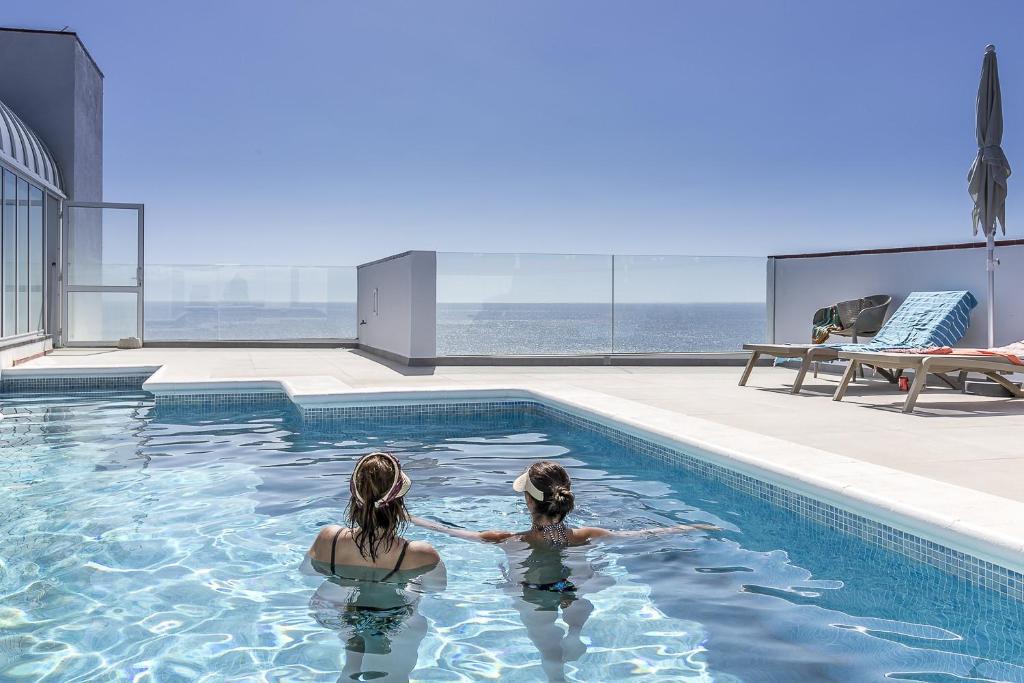 two women in the swimming pool of a building at EDEN RENTALS Seaside Getaway in Puerto de Santiago