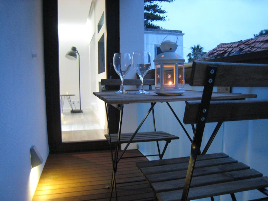 a table with two wine glasses and a candle on a balcony at Cascais FEELINGS in Cascais