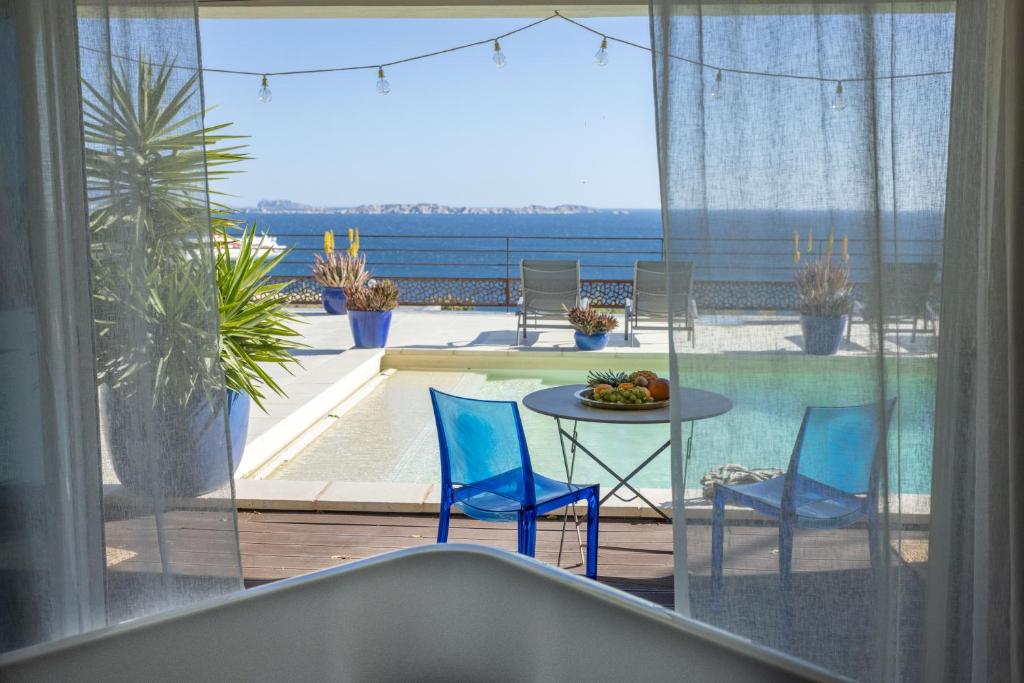 a balcony with a table and two blue chairs at LES SUITES LOVE 2 SPA VUE MER PISCINe in Marseille