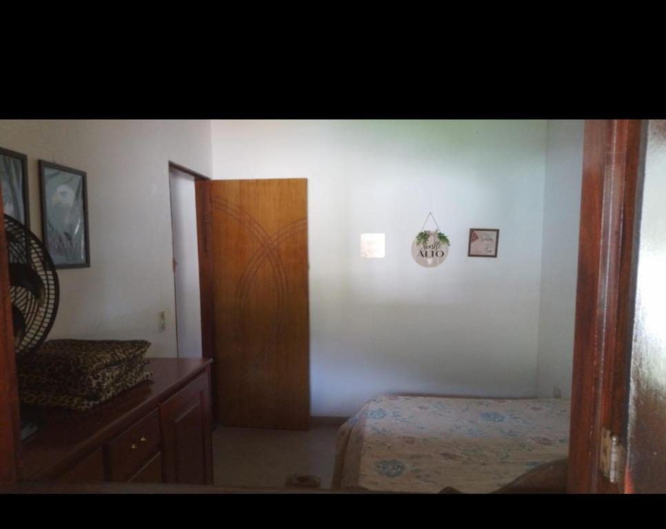 1 dormitorio con 1 cama y puerta de madera en casa temporada da Cris, en Paraty