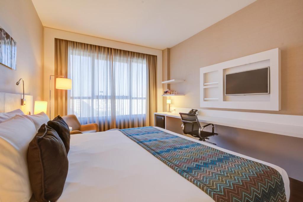 サン・カエタノ・ド・スルにあるQuality Hotel São Caetanoのベッド1台、薄型テレビが備わるホテルルームです。