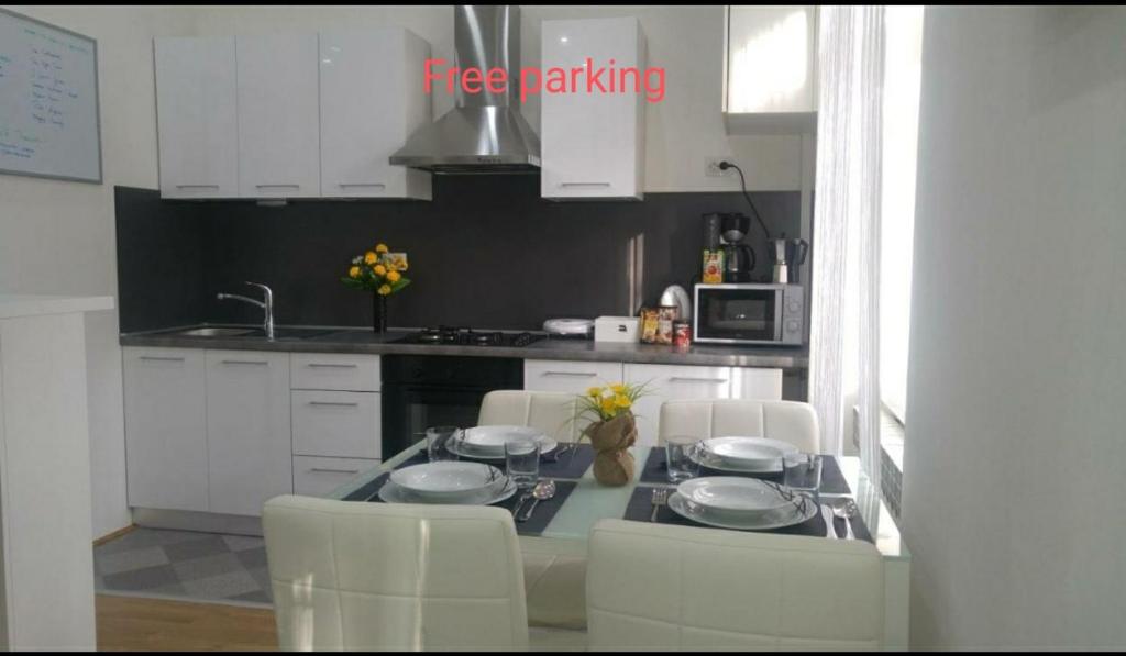 una cucina con armadi bianchi e un tavolo con tre piatti di Apartments Zagreb Center a Zagabria