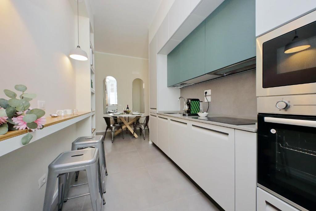 a kitchen with white cabinets and a table and chairs at Montebello - Rooms in Rome