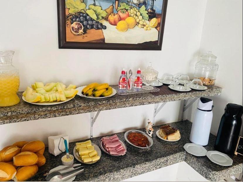 a counter with plates of food and plates of fruit at Beijaflor Pousada in Corumbá