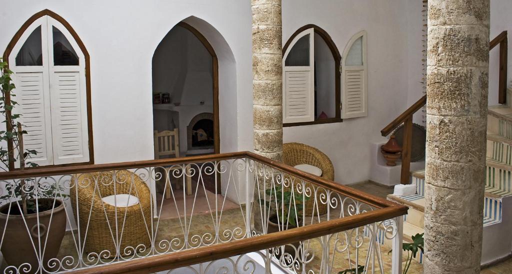 a staircase in a house with chairs and windows at Dar Lazuli Bed & Breakfast in Essaouira