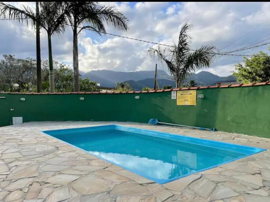 uma piscina em frente a uma parede verde em Apartamento completo Ubatuba - Maranduba em Ubatuba