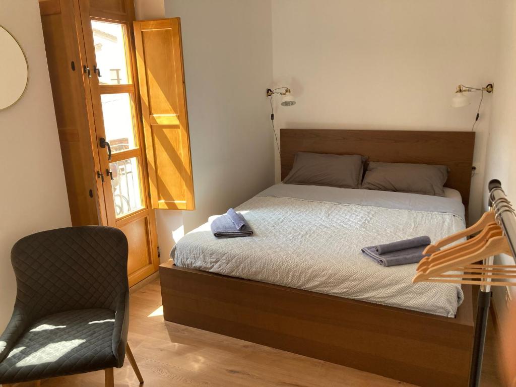 a bedroom with a bed with a chair and a window at Sagunto Castillo 17 in Sagunto