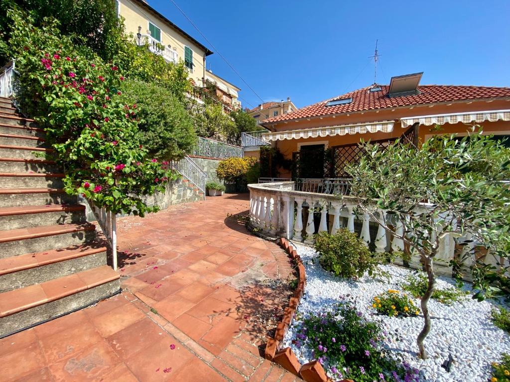 a house with a staircase and a yard with flowers at Casa Ribot: Alassio centro e mare a portata di mano in Alassio