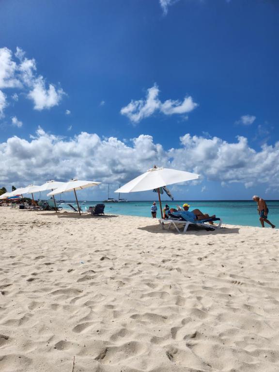 - un groupe de parasols blancs sur une plage dans l'établissement Tierra Del Sol...OCEAN FRONT GOLF AND TENNIS RESORT CONDO, à Palm-Eagle Beach