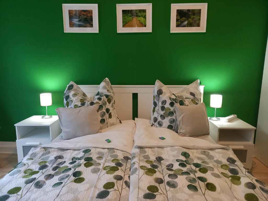 ein grünes Schlafzimmer mit einem Bett und zwei Nachttischen in der Unterkunft Ferienwohnung Xenia in Pirna