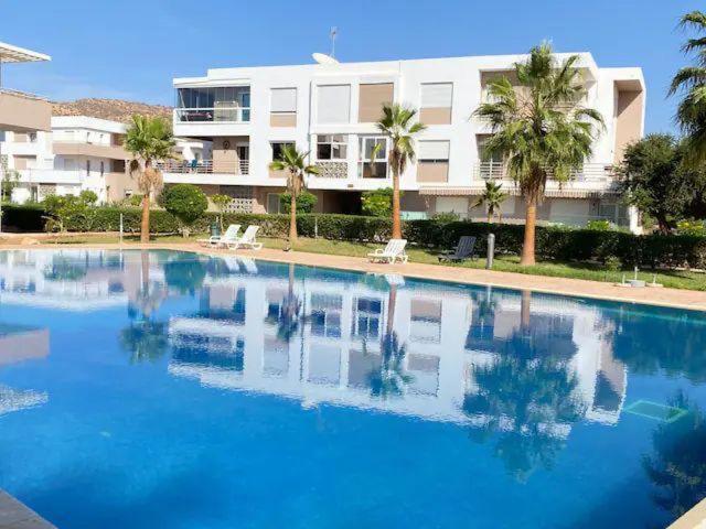 a large blue swimming pool in front of a building at Appartement avec piscine taghazout imi Ouaddar in Agadir nʼ Aït Sa