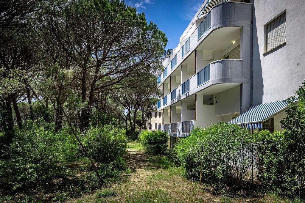 un immeuble d'appartements avec des buissons devant lui dans l'établissement Residence Mareblù, à Principina a Mare