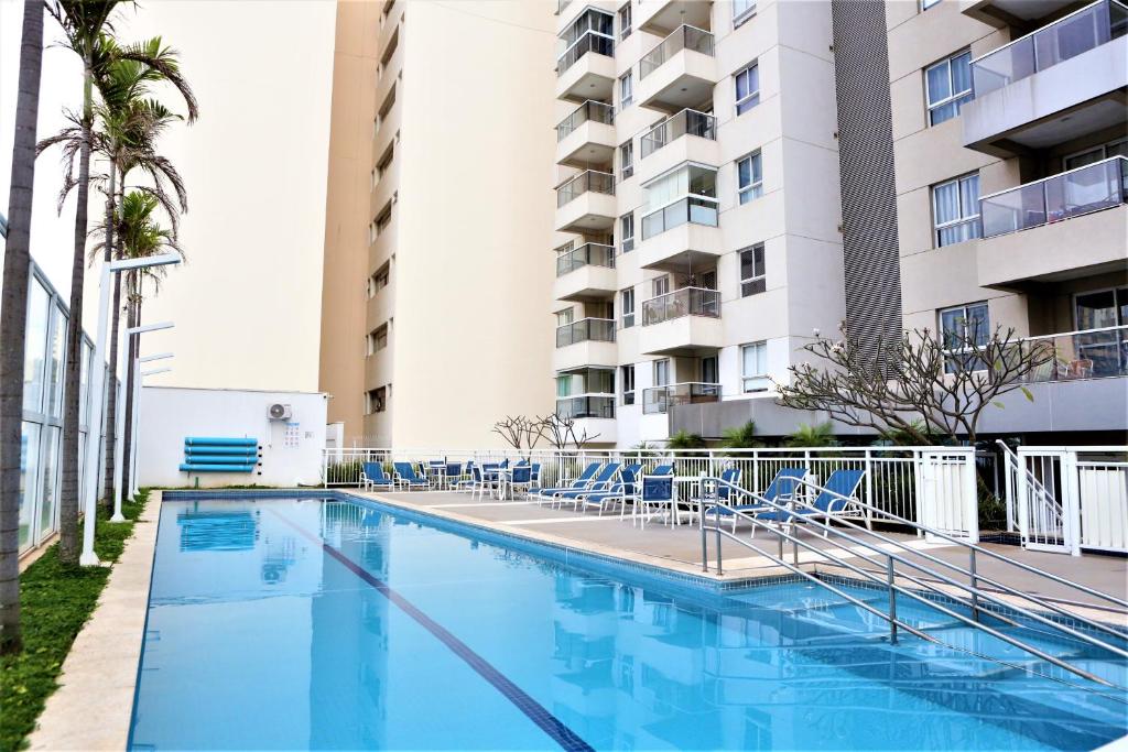 a swimming pool with chairs and a building at Apartamento 1903 no Bosque com quarto cozinha completa e vaga de garagem in Campinas