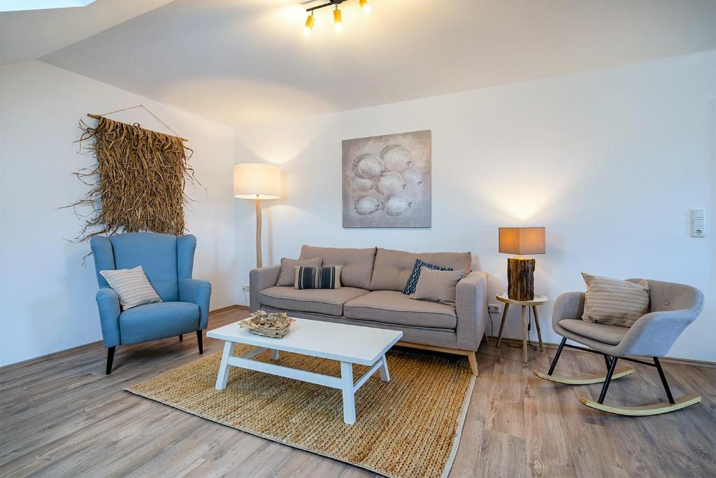 a living room with a couch and two chairs and a table at Meereszeiten in Greetsiel