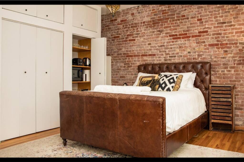 a bedroom with a large bed and a brick wall at Prime Studio Greenwich Village! in New York