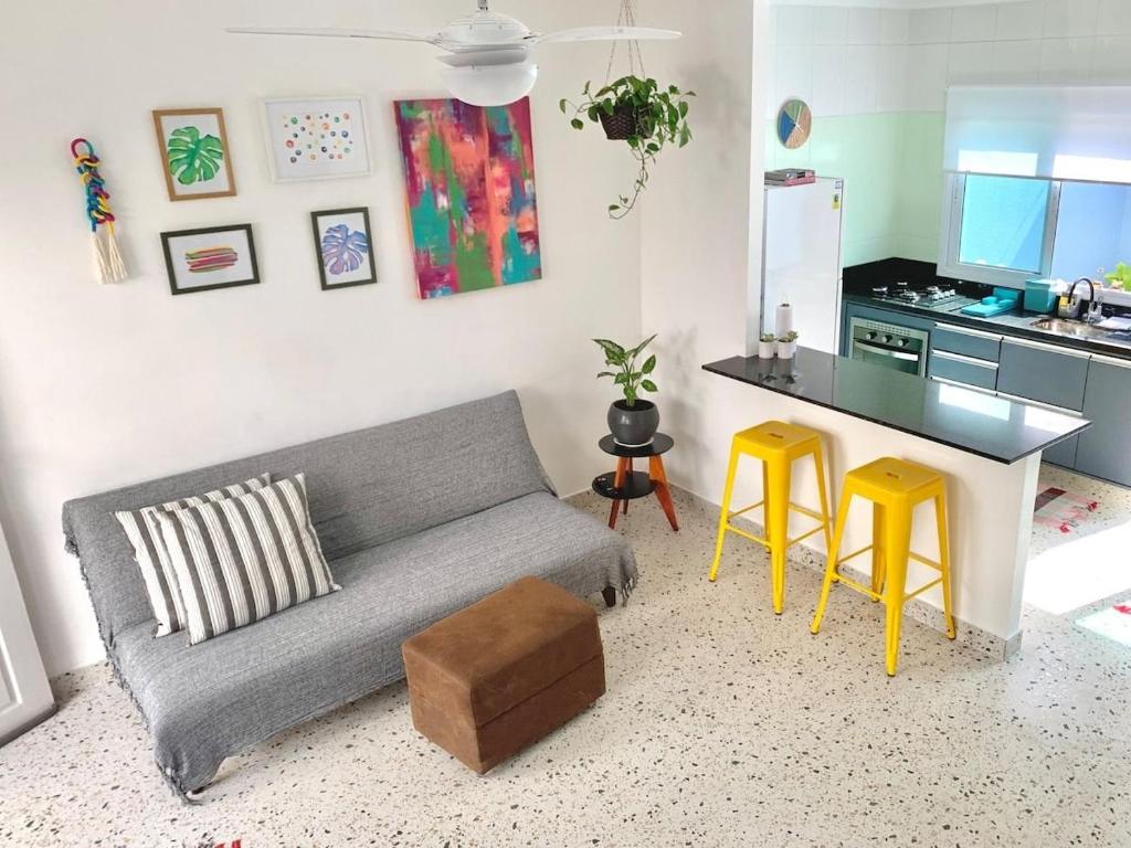 sala de estar con sofá gris y taburetes amarillos en Casa Marola: 100M da Praia, Completa e Tranquila, en Bertioga