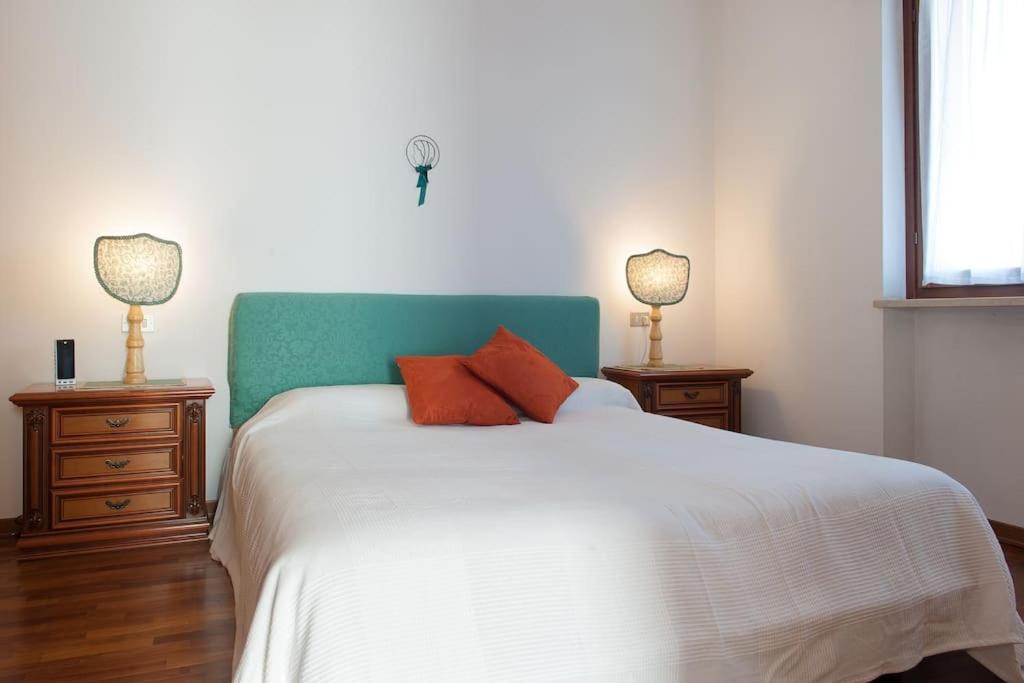 een slaapkamer met een wit bed met 2 nachtkastjes en 2 lampen bij Appartamento con garage vicino al centro in Verona