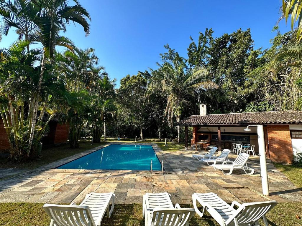 - une piscine avec des chaises et une maison dans l'établissement Casa com Piscina e Churrasqueira na Riviera em Bertioga, à Riviera de São Lourenço