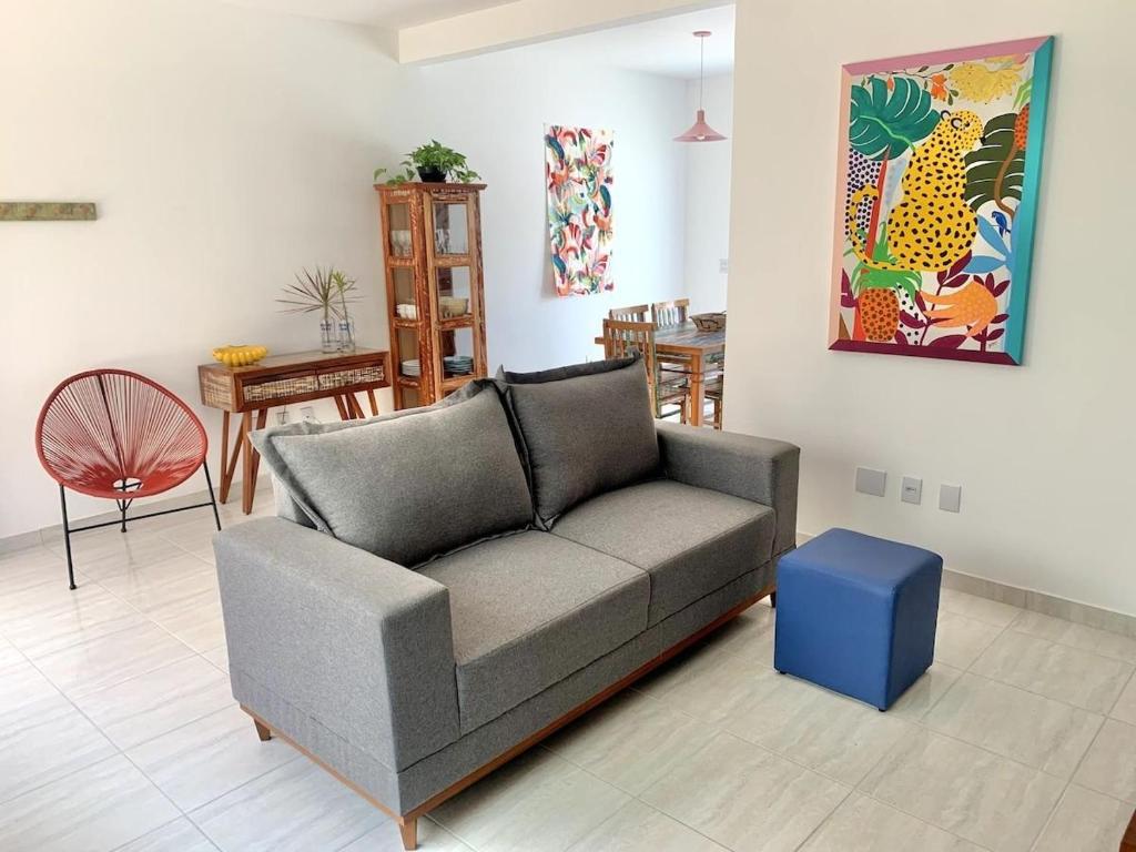 ein Wohnzimmer mit einem grauen Sofa und einem blauen Stuhl in der Unterkunft Casa das Marés: 100M Praia da Enseada - Tranquila e Completa in Bertioga