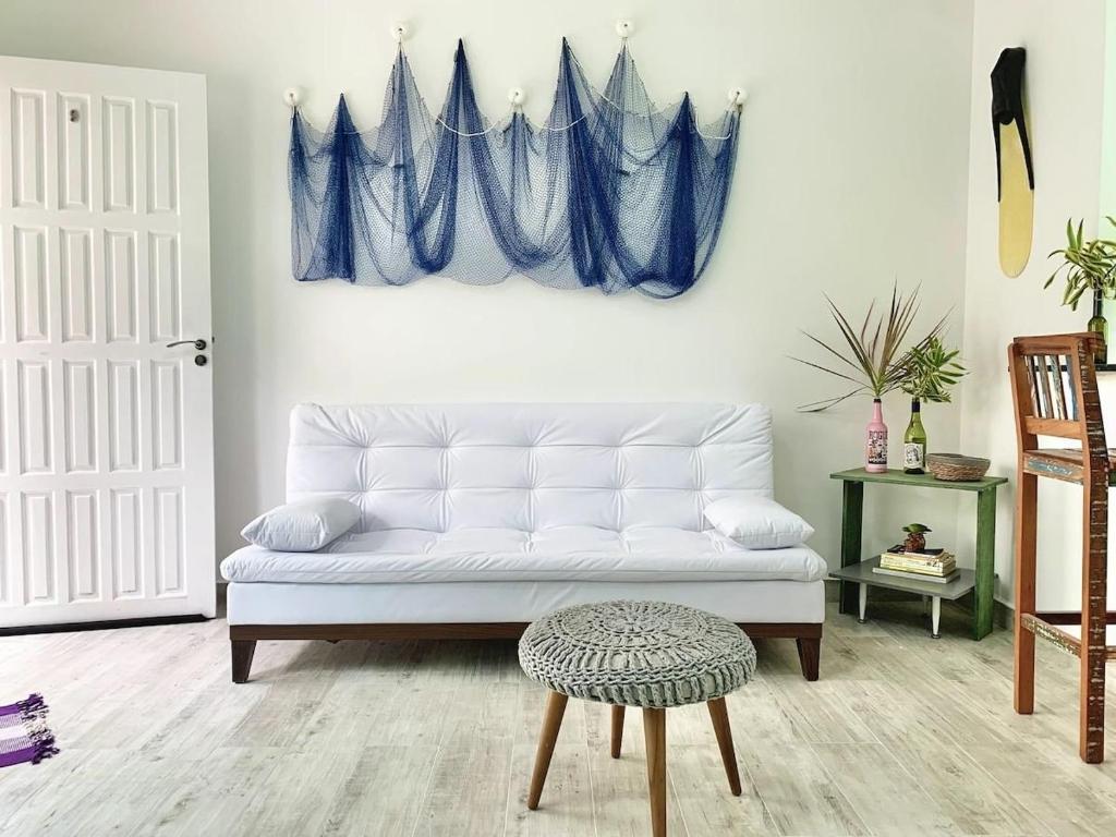 ein Wohnzimmer mit einem weißen Sofa und einem blauen Vorhang in der Unterkunft Casa Maré Mansa: in Bertioga