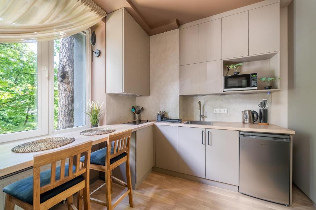 Una cocina con gabinetes blancos y una mesa y sillas. en Dzintaru 48 studio, en Jūrmala