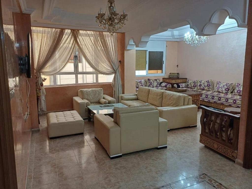 una sala de estar con sofás y una lámpara de araña. en Appartement familiale méditerranéen en Alhucemas