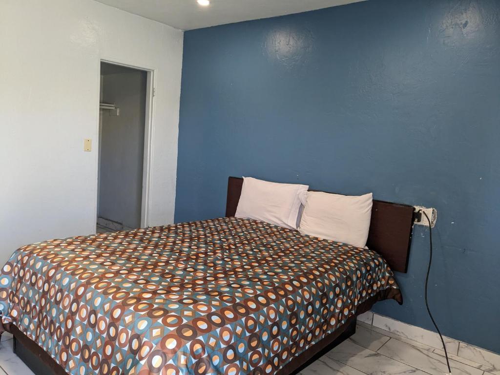 a bedroom with a bed with a blue wall at Green spot motel in Victorville