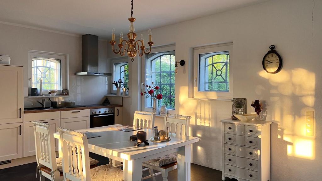a kitchen with a white table and chairs and windows at Ferienhaus Villa Vogelsang (Schlei / Ostsee) in Stoltebüll