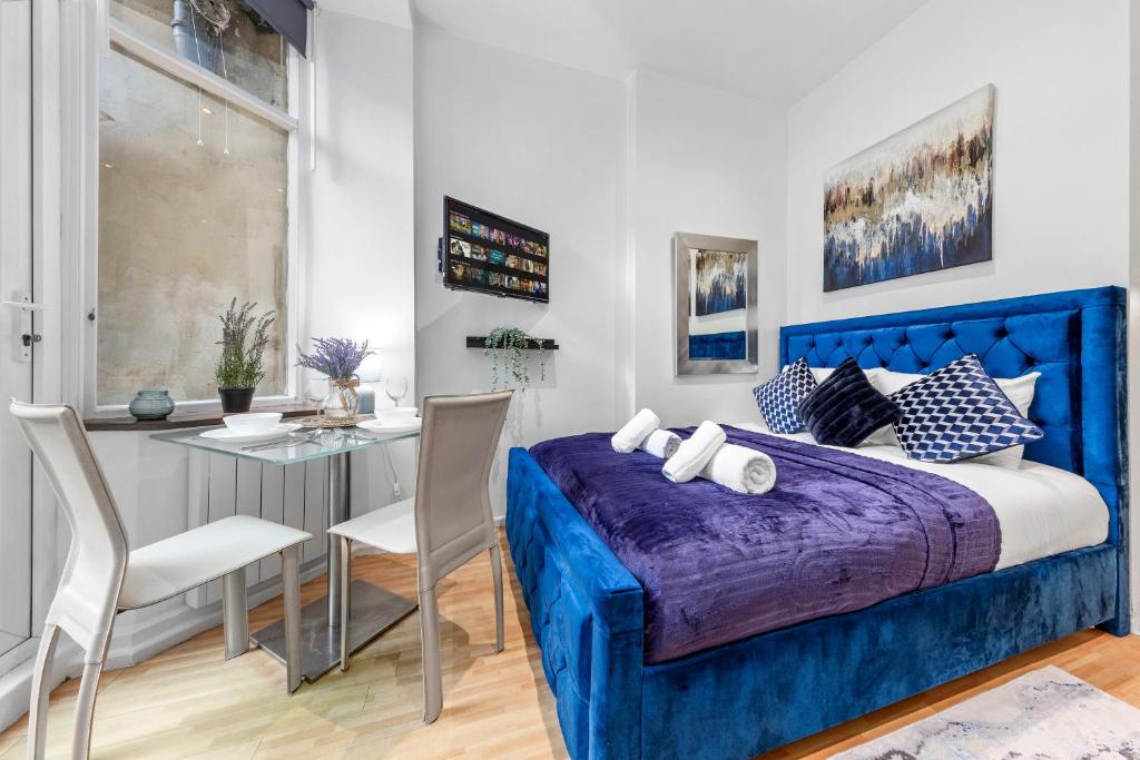 Schlafzimmer mit einem blauen Bett, einem Tisch und Stühlen in der Unterkunft Immaculate 1-Bed Studio in London in London