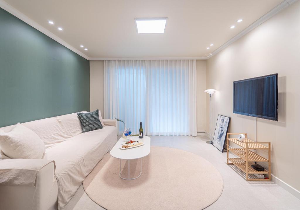a living room with a white couch and a tv at Osondoson Stay in Seoul