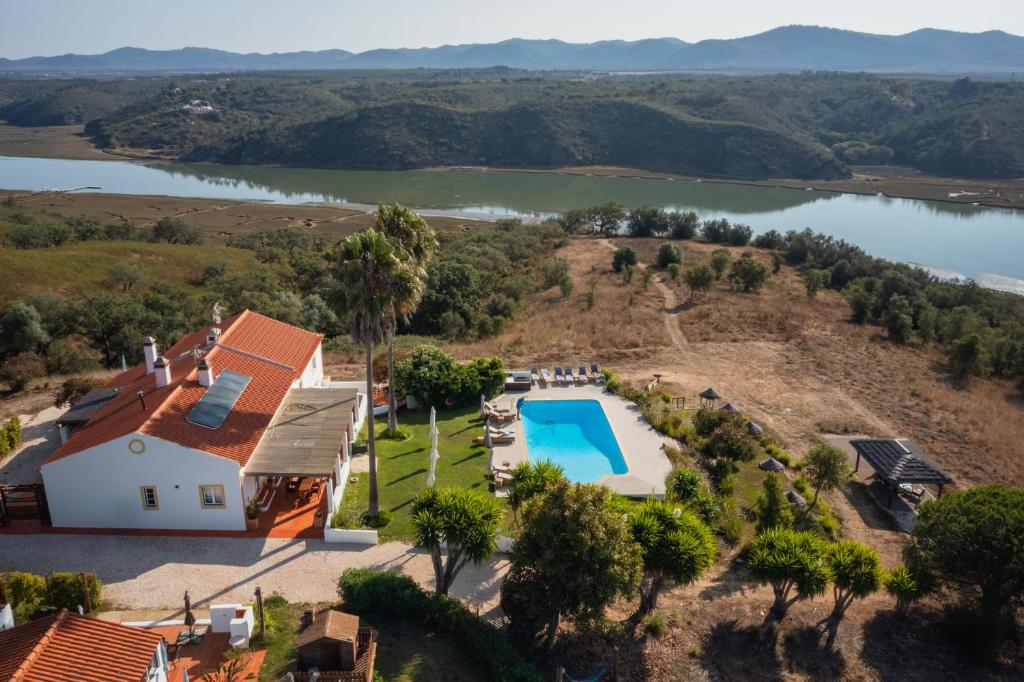 an aerial view of a house with a swimming pool and a lake at Monte Do Zambujeiro in Vila Nova de Milfontes