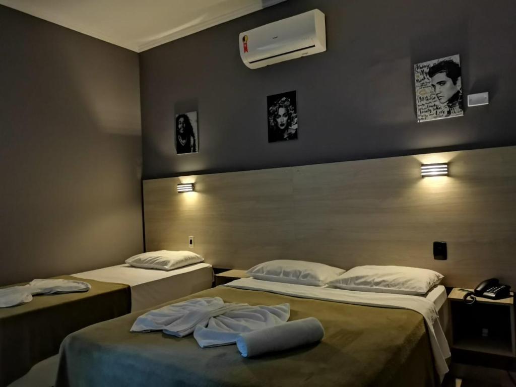 twee bedden in een hotelkamer met handdoeken erop bij POUSADA NOSSO LAR in Guarujá