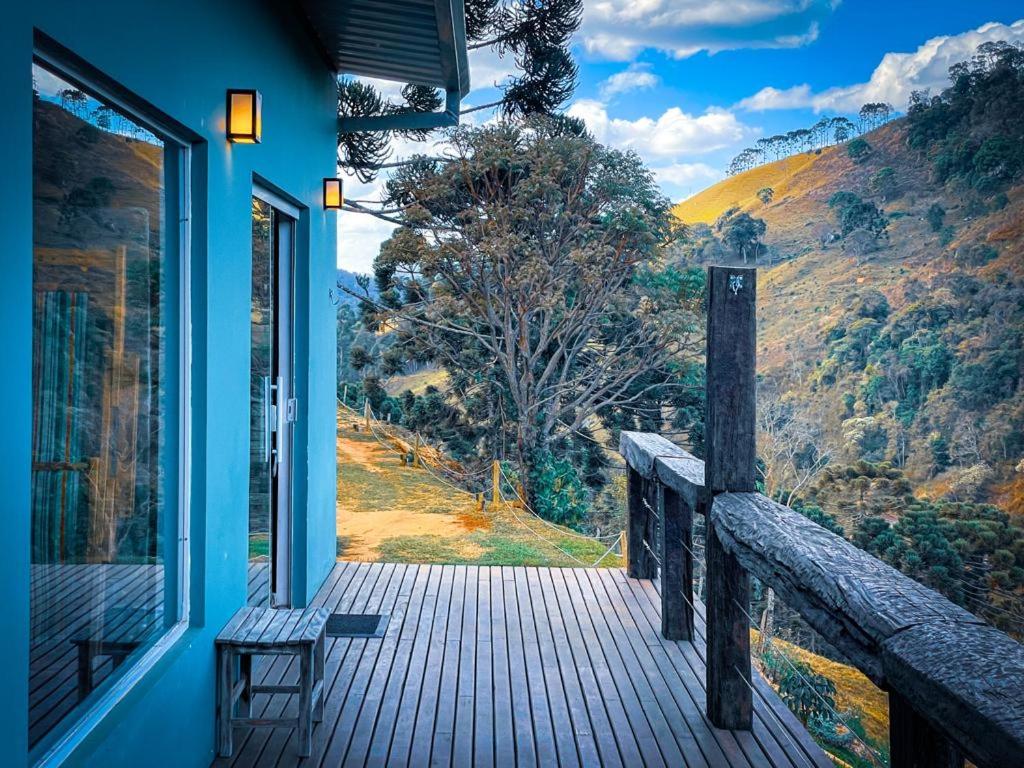 un porche de una casa azul con un banco. en Pousada Espelho Dagua en Gonçalves
