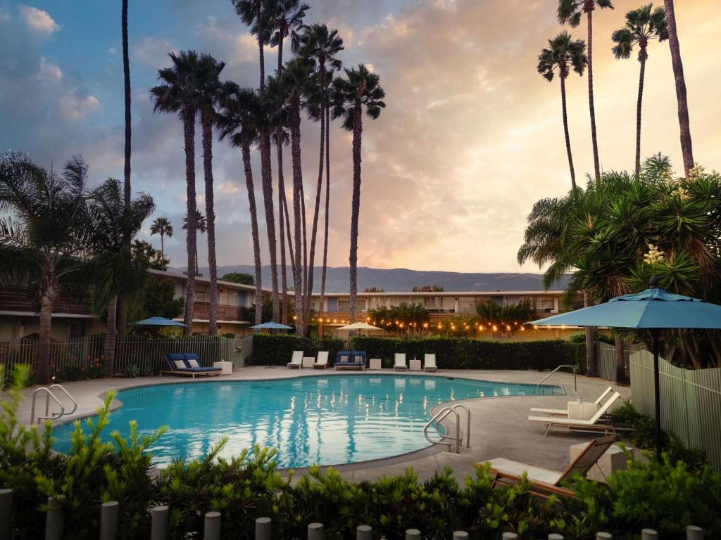 a pool at a resort with palm trees at The Leta Santa Barbara Goleta, Tapestry Collection by Hilton in Santa Barbara