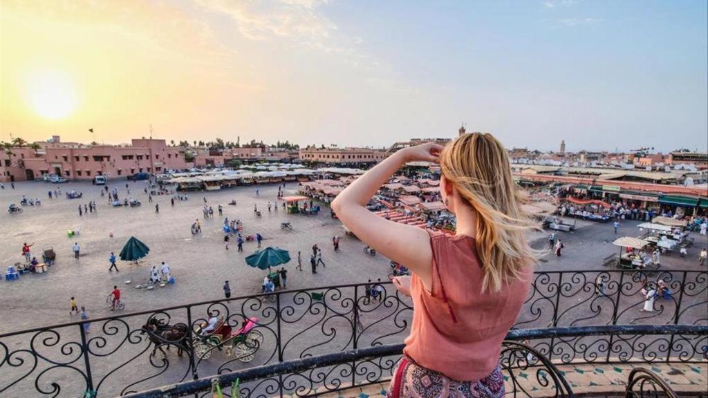 a woman standing on a balcony looking at a city at DAR ESSHRA in Marrakesh