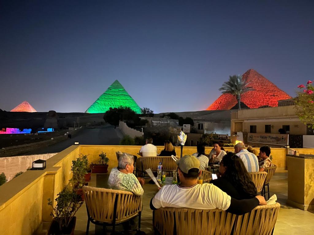 a group of people sitting in chairs on a balcony with pyramids at The Gate Hotel Front Pyramids & Sphinx View in Cairo