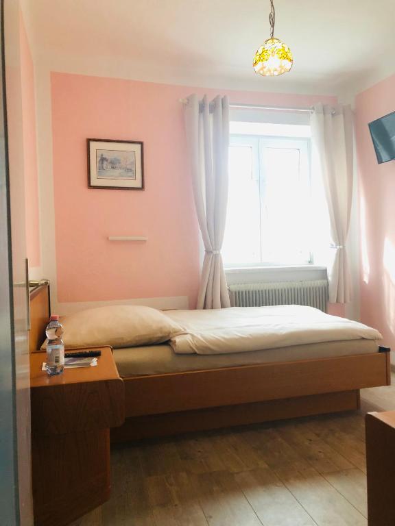 a bedroom with a bed with a window and a table at Holmes Café & Pension in Engelhartszell