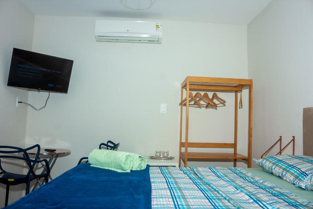 a room with a bed and a tv and a table at Suíte Peixe Espada in Praia do Forte