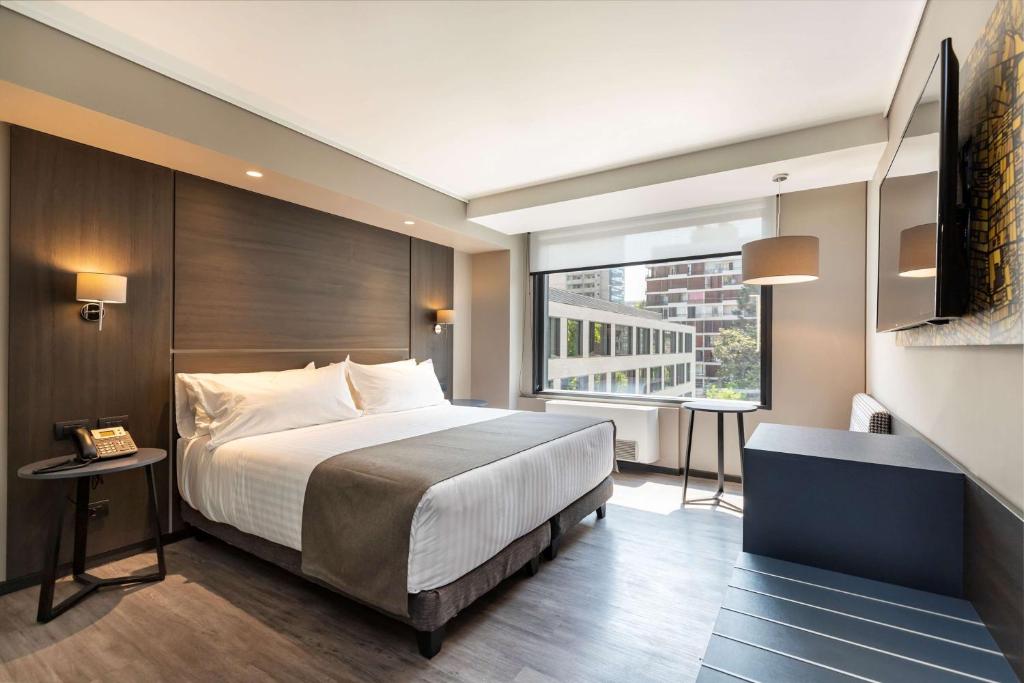 a bedroom with a large bed and a large window at Ola Santiago Providencia, Tapestry Collection by Hilton in Santiago