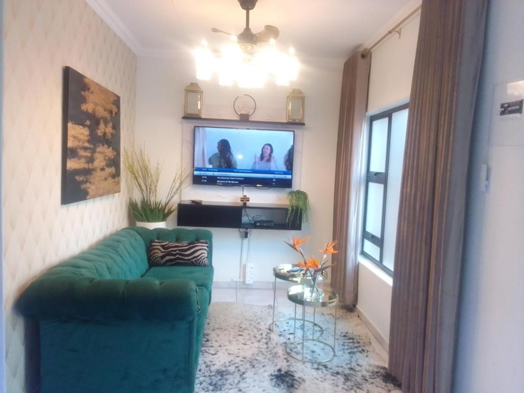 a living room with a green couch and a television at Elegant Airbnb in Pretoria