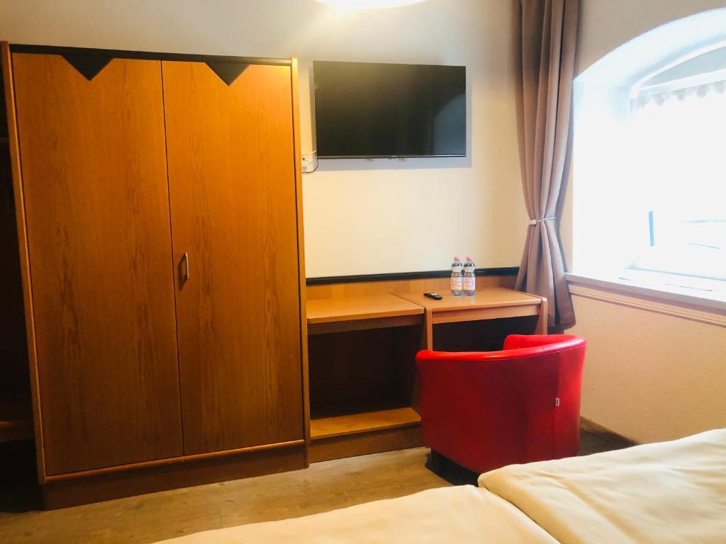 a bedroom with a cabinet and a desk with a tv at Holmes Café & Pension in Engelhartszell