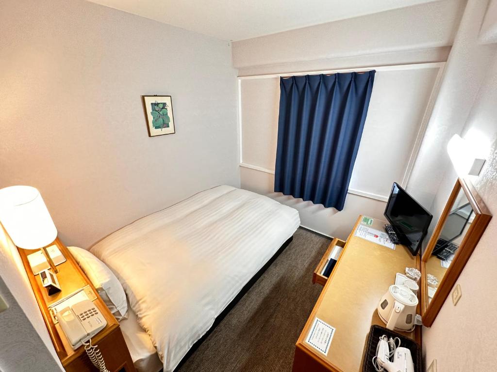 mały pokój hotelowy z łóżkiem i oknem w obiekcie Hotel New Saitama w mieście Saitama