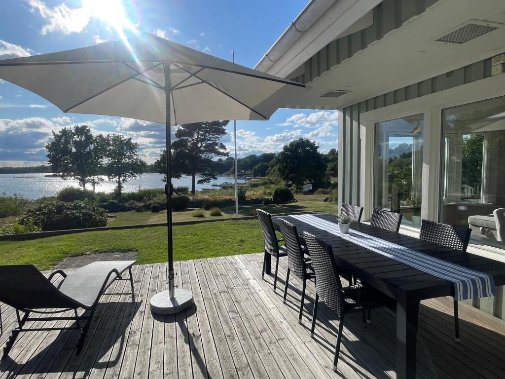 une terrasse avec une table, des chaises et un parasol dans l'établissement Seaside Home with Stunning Views Overlooking Blekinge Archipelago, à Ronneby