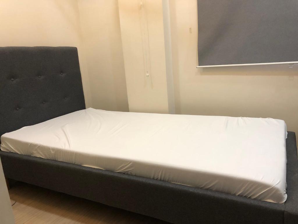 a bed in a room with a black bed frame at Comfy Room With Single Sized Bed, Study Space, Closet, and WiFi in Manila