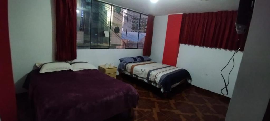 2 camas en una habitación con paredes rojas y blancas en Hotel Águila Real, en Huancayo